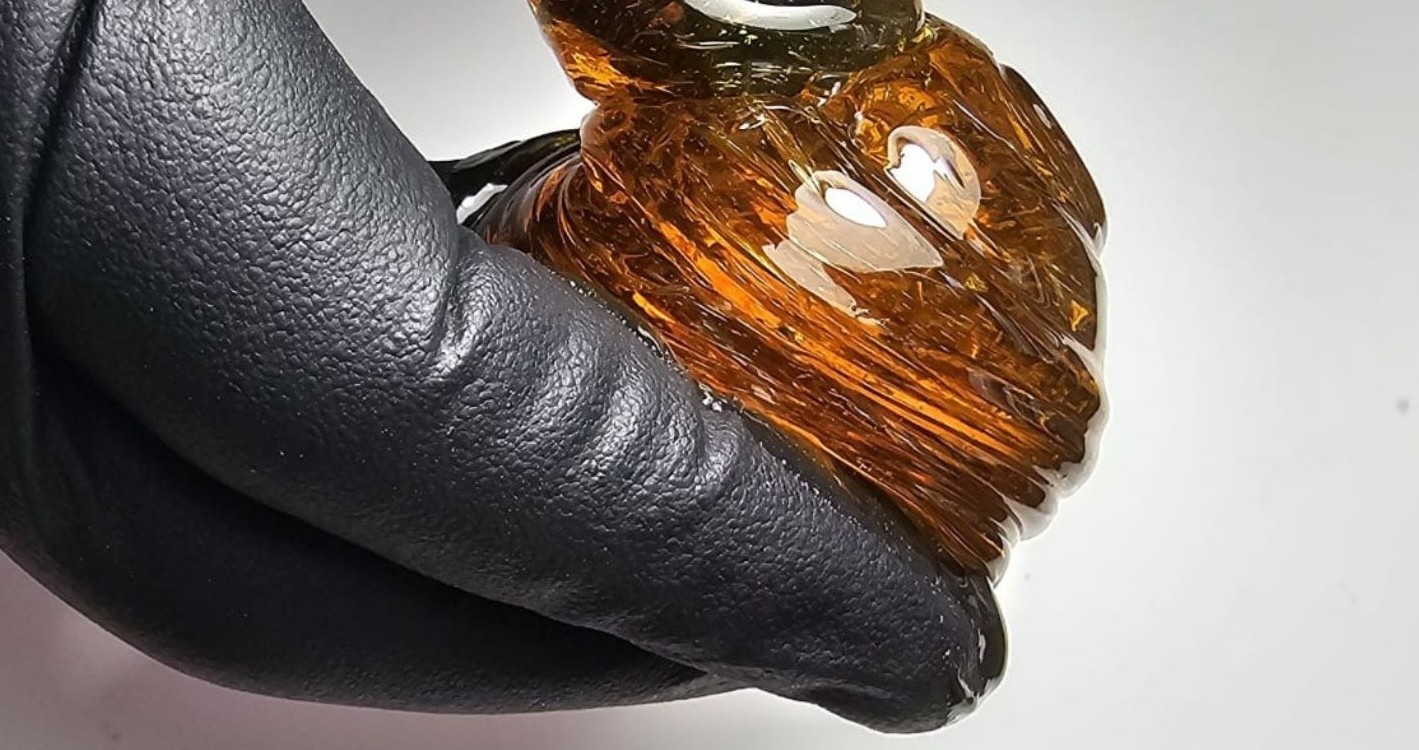 Een bol amberkleurige suikerpasta in een zwarte handschoen