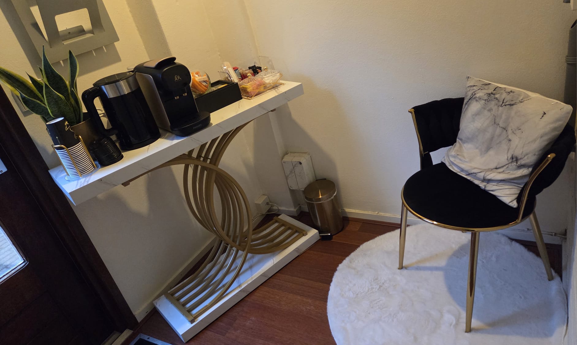 Zithoek met een zwarte stoel op een rond wit kleed en een gouden wandtafel