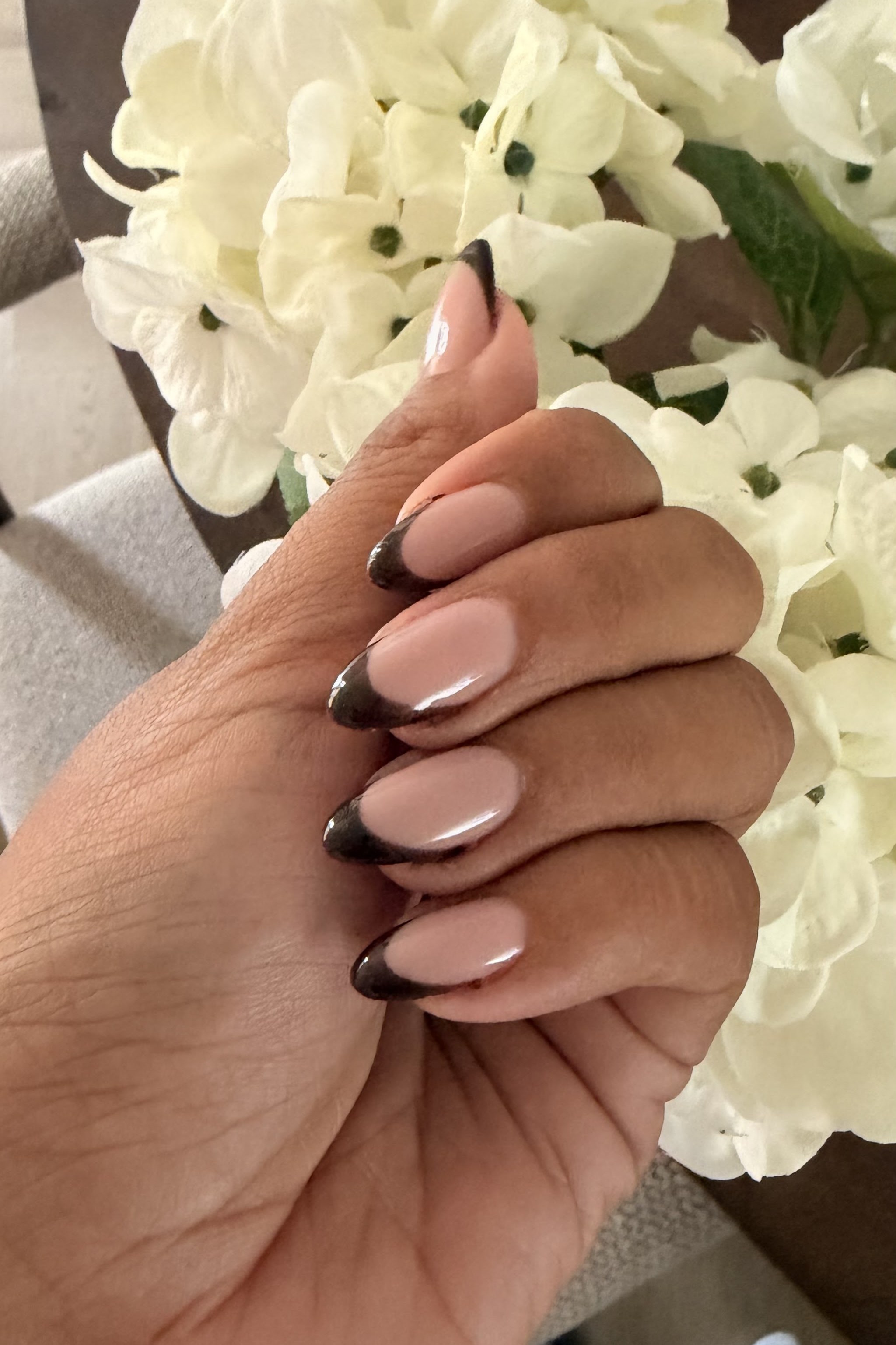 Amandelvormige nagels met een donkere French tip tegen witte bloemen